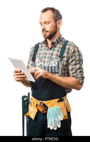 handsome plumber with tool belt using tablet isolated on white Stock Photo