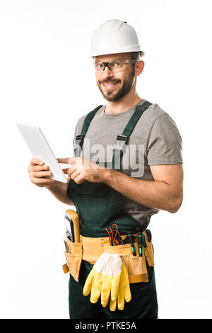smiling handsome electrician in helmet and protective glasses using tablet isolated on white Stock Photo