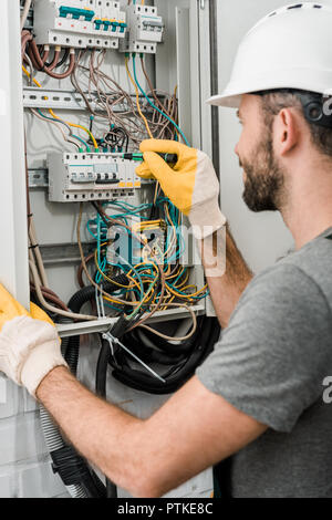 side view of electrician repairing electrical box and using screwdriver in corridor Stock Photo