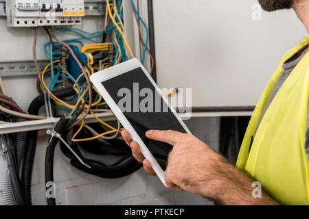 cropped image of electrician using tablet near electrical box in corridor Stock Photo