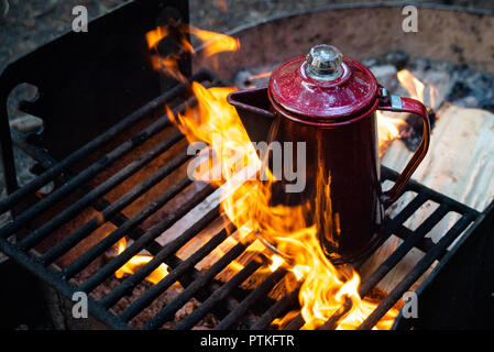 Enjoying a cup of coffee over a campfire in the early morning at sunrise while camping at Lake Crescent in Washington. Stock Photo