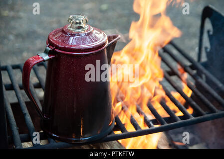 Enjoying a cup of coffee over a campfire in the early morning at sunrise while camping at Lake Crescent in Washington. Stock Photo