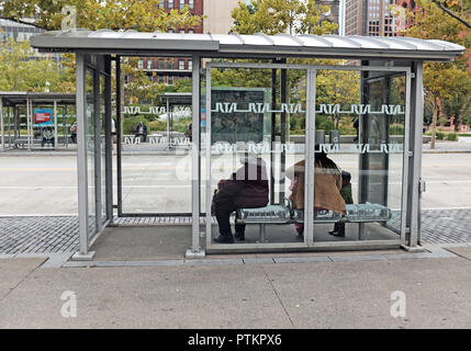 Women wait in a public bus shelter on public square in downtown Cleveland, Ohio, USA. Stock Photo