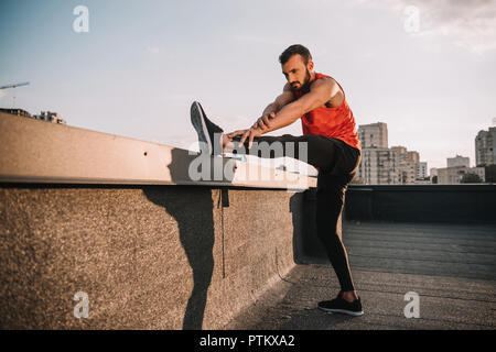 handsome sportsman stretching legs on roof Stock Photo