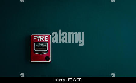 Fire alarm on dark green concrete wall. Warning and security system. Emergency equipment for safety alert. Red box of fire alarm on wall of school, ho Stock Photo