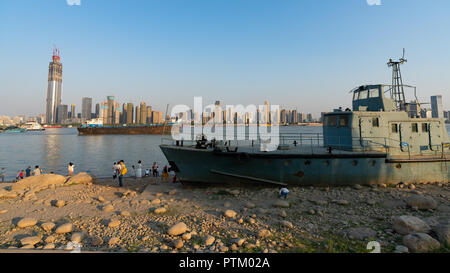 4 October 2018, Wuhan China : Wreck of Chinese naval ship wash ashore on Yangtze riverbank and Wuhan skyline in background in Wuhan Hubei China Stock Photo