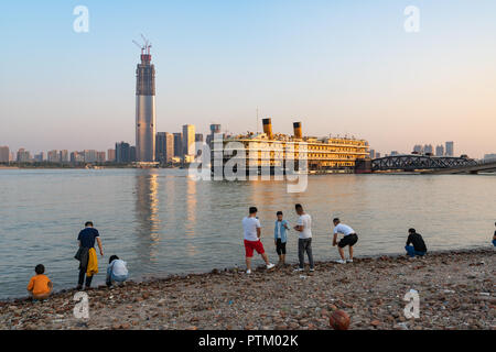 4 October 2018, Wuhan China : people on Yangtze riverbank and Zhiyin Hao cruise boat and Wuhan skyline in background Stock Photo