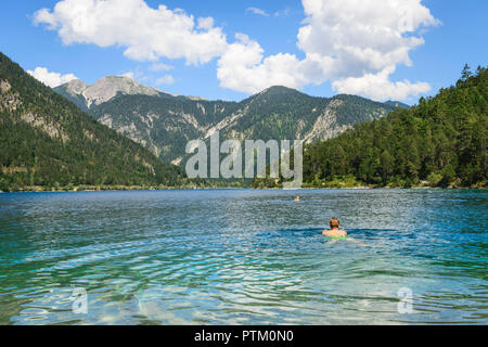 Young man bathing, swimming in Lake Plansee, turquoise water, mountain lake, mountain landscape, Tyrolean Alps, Reutte, Tyrol Stock Photo