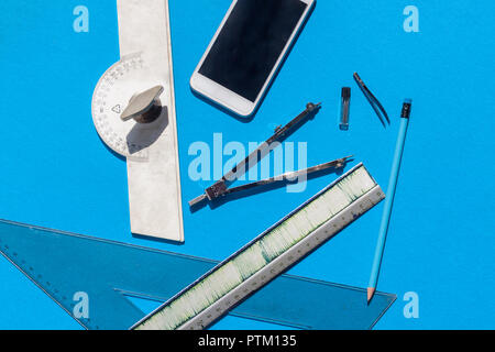 Geometry set with compass, rulers, pencil and protractor on blue background - top view Stock Photo