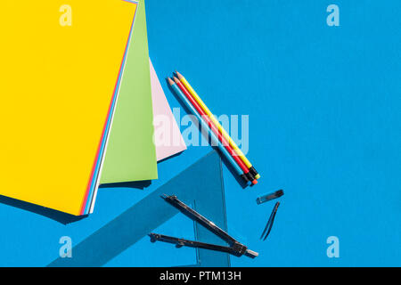 Geometry set with sheets colorful papers, compass, rulers and pencils on blue background - top view Stock Photo