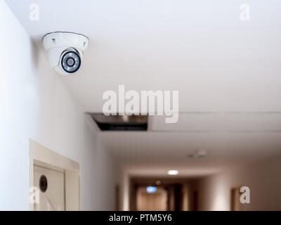 White security CCTV Camera or surveillance operating on ceiling in front of the door room in condominium with copy space. Stock Photo
