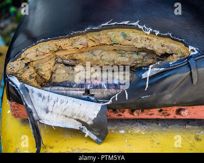 Old and torn damaged leather seat of old forklifts with visible sponge and wood inside. Stock Photo