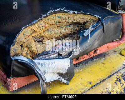 Old and torn damaged leather seat of old forklifts with visible sponge and wood inside. Stock Photo