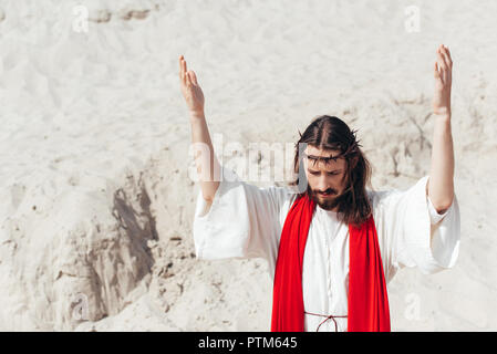 Jesus standing with raised hands and praying in desert Stock Photo