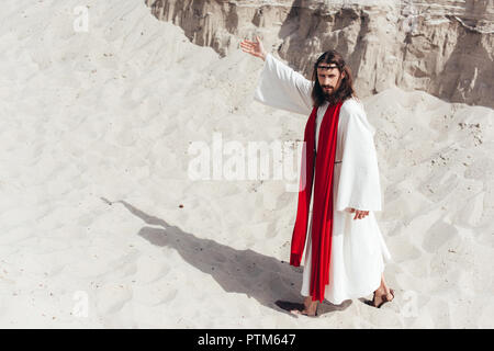 Jesus In Robe Red Sash And Crown Of Thorns Holding Rosary And Protecting  Face From Light In Desert Stock Photo - Download Image Now - iStock