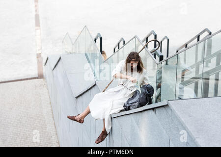 high angle view of Jesus in robe and crown of thorns sitting on staircase side and putting map in bag Stock Photo