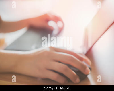 Blurred hands working with laptop computer background. Right hand clicking on mouse and left hand typing on keyboard. Stock Photo