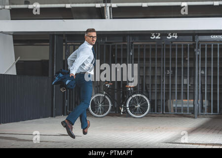 handsome middle aged buisnessman in eyeglasses looking at camera while running to bike Stock Photo