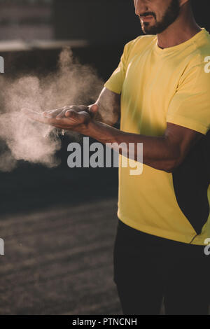 cropped image of sportive man clapping hands with talc powder on roof Stock Photo