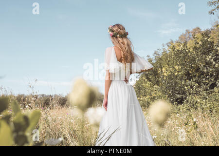 back view of tender young blonde bride walking on beautiful field Stock Photo