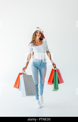 attractive happy girl in santa hat walking with shopping bags, isolated on white Stock Photo