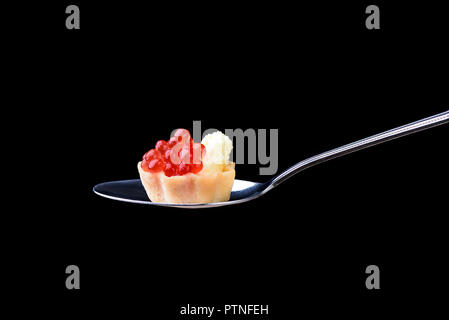 Tartlet with red caviar and butter on a tablespoon on a black ba Stock Photo