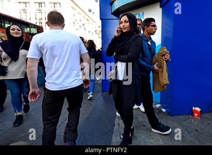 Asian woman wearing a headscarf using her mobile phone, London, England, UK. Stock Photo