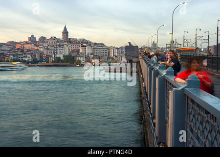 Galata bridge with fishermen fishing in late afternoon light, Karakoy and Galata Tower can be seen in the distance, Istanbul, Turkey Stock Photo