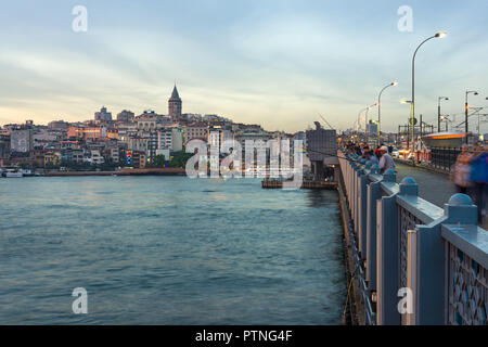 Galata bridge with fishermen fishing in late afternoon light, Karakoy and Galata Tower can be seen in the distance, Istanbul, Turkey Stock Photo