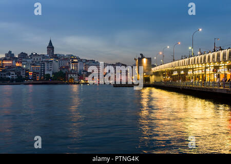 Galata bridge with fishermen fishing at dusk, Karakoy and Galata Tower can be seen in the distance, Istanbul, Turkey Stock Photo