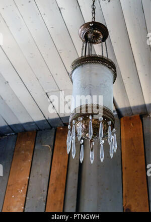 Antique hanging lamp, white engraved cylinder shape with brass ornate trim & chandelier type prisms. Chestnut Square Historic Village, McKinney,Texas. Stock Photo