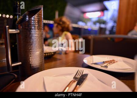A restaurant table with empty plates and a child in the background, Townsville, Queensland, Australia Stock Photo