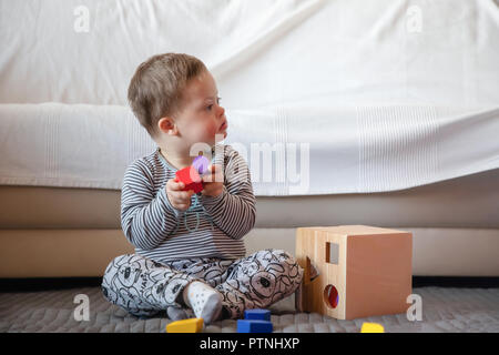 Portrait of cute boy with Down syndrome playing in home Stock Photo