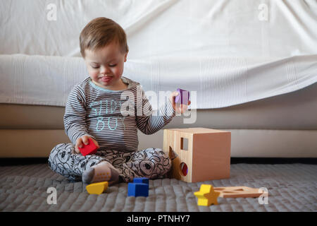 Portrait of cute boy with Down syndrome playing in home