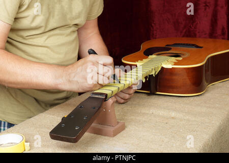 Musical instrument guitar repair and service - Worker preparation of frets for grinding acoustic guitar Stock Photo