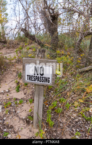 No Trespassing sign in front of wooded, sandy area. Stock Photo