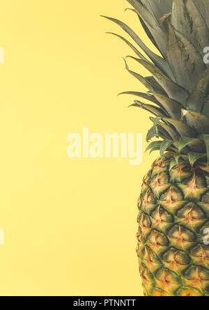 A close up of a whole pineapple showing the textured and patterned outer skin, healthy, fresh leaves and copy space on a yellow background Stock Photo