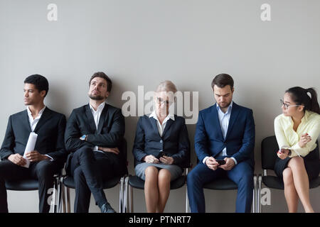 Diverse job candidates sitting waiting in queue for interview Stock Photo