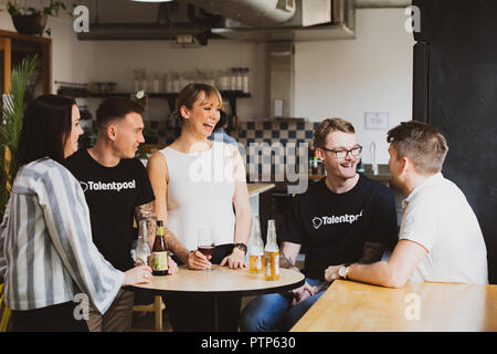 Businesspeople relax after a hard day's work with a few drinks in a co-working space Stock Photo