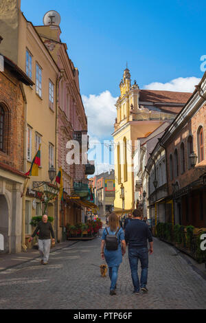 Vilnius old town street, rear view of a young couple walking along Pilies Gatve - the main thoroughfare in the center of Vilnius Old Town, Lithuania. Stock Photo