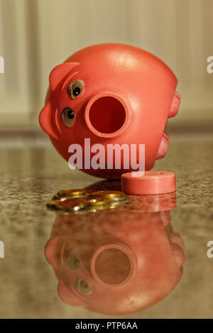 Pink piggy bank with nose taken off and money taken out and on counter Stock Photo