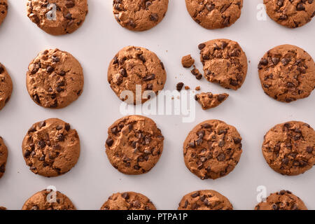 Breakfast with round biscuits pattern with black chocolate chips on white table in kitchen. Top view. Horizontal composition Stock Photo