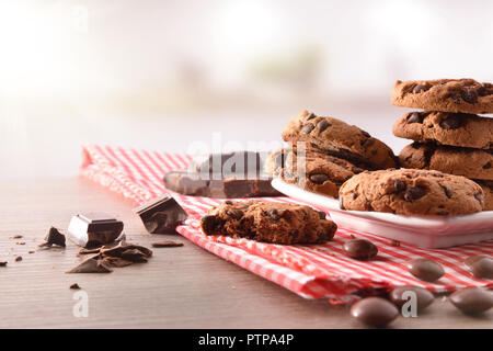 Breakfast with round biscuits with black chocolate nuggets on tablecloth and wooden kitchen table. Front view. Horizontal composition Stock Photo