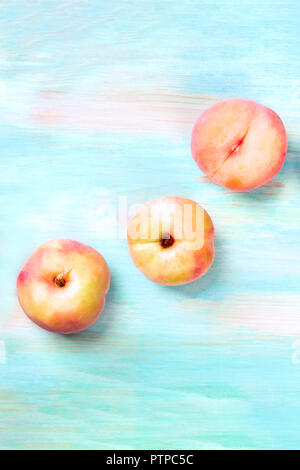 An overhead photo of vibrant organic flat saturn peaches, shot from above on a teal background with copyspace Stock Photo