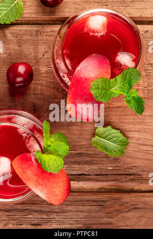 Overhead photo of vibrant red drinks with cherries on a rustic background with copyspace Stock Photo