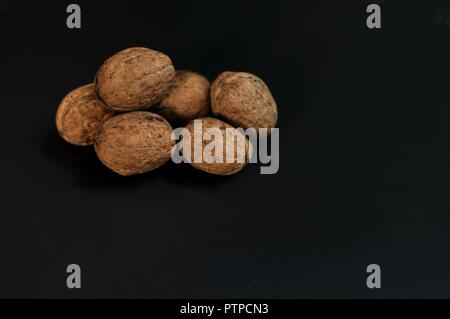 Heap (pile, stack) of nuts in shell isolated on black background with copy space. Underexposed, front side view Stock Photo