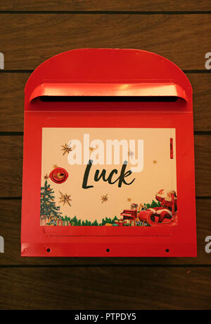 The Positive Word Luck on Vibrant Red Post Box Hanging on the Wooden Wall for Festive Season Stock Photo