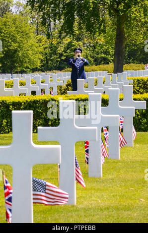 Memorial Day US service bugler playing among the memorial crosses at the Cambridge American Cemetery and Memorial. Grave headstones and flags Stock Photo
