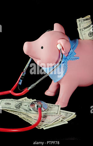 Piggy bank with medical stethoscope on a pile of money isolated on black Stock Photo