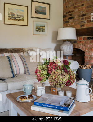 Hydrangeas on coffee table with books and cups in 18th century Norfolk cottage Stock Photo